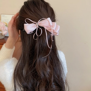 Detail of light pink satin bow hair clip with zircon embellishment on brunette hair