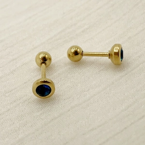 Detailed macro view of golden titanium steel stud earrings with navy blue round zircon stones