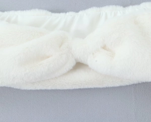 Gros plan d'un bandeau en peluche blanche avec nœud torsadé en fausse fourrure douce