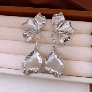 Boucles d'oreilles fleurs argentées avec texture métallique plissée sur boîte à bijoux