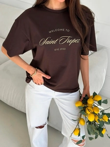 Loose dark brown cotton T-shirt featuring golden Saint Tropez artistic print on model
