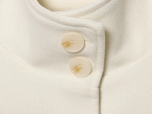 Detail view of white wool blend cape coat collar with two beige four-hole buttons