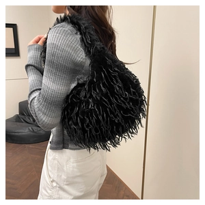 Detail showing the fluffy texture and long fringe of this black faux fur shoulder bag