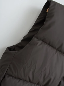 Detailed close-up of dark brown quilted puffer vest showing shoulder seams and fabric texture