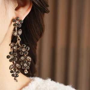 Detail of vintage gold flower tassel earrings with crystals on a textured fabric
