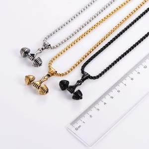 Close-up of three stainless steel dumbbell pendants in gold, silver, and black with ruler scale