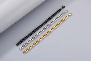 Macro detail of curb chain bracelets in black, silver and gold with lobster clasps