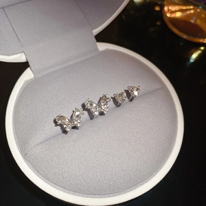 Close-up of heart and butterfly stud earrings set with sparkling stones in a gray velvet box