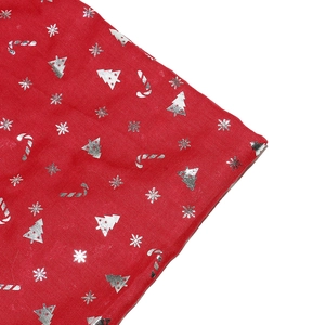 Detailed view of red Christmas fabric with silver snowflake and tree foil prints