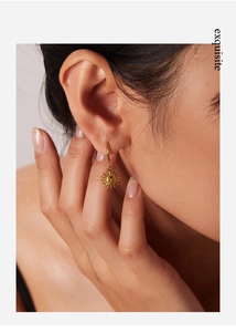 Detailed close-up of 18k gold-plated sun charm hoop earring with facial relief