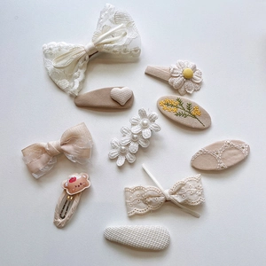 Detailed view of embroidery bow hair clips and lace floral hairpins set in cream colors