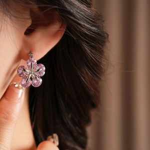 Gros plan d'une boucle d'oreille fleur en argent avec zircons roses sur l'oreille