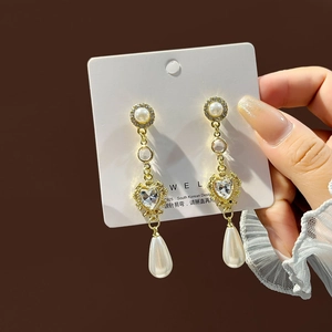Elegant long pearl earrings with heart zircon and S925 silver needle on brown background