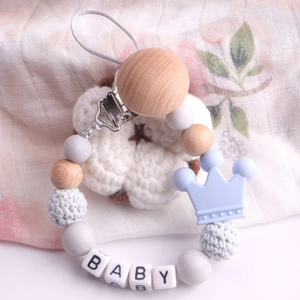 Detail of wooden pacifier clip with baby letter beads and blue silicone crown charm