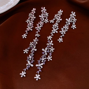 Detail of silver drop earrings featuring zircon flower tassels on a velvet background