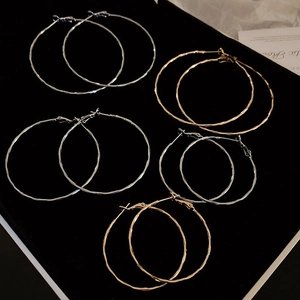 Macro detail of textured gold and silver hoop earrings on a black velvet display
