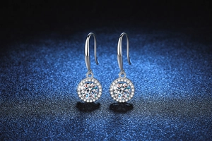 Detailed view of silver moissanite drop earrings with classic round halo on dark background