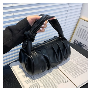 Detail of a black pleated cloud bag with a knotted handle and soft leather texture