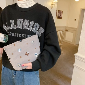 Handheld view of a grey linen pouch featuring colorful embroidered cat head designs