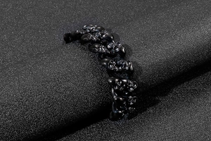 Macro shot of punk black skull link ring with matte gothic finish on textured surface