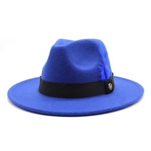 Détail d'un chapeau fedora en feutre bleu roi avec ruban noir, plume et emblème M doré
