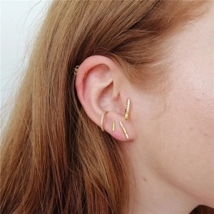 Detail of gold floral ear cuff set with rhinestones worn on ear in a layered style