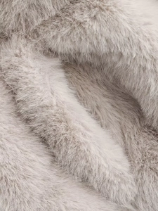 Vue macro de la fausse fourrure haute densité montrant la texture douce et le ton beige gris