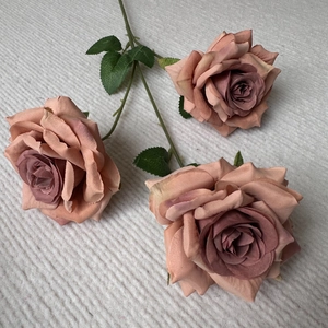 Detailed view of artificial pink and purple roses with three heads and green stems