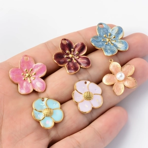 Hand holding colorful stainless steel cherry blossom pendants for DIY jewelry making