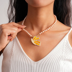 Détail d'un pendentif papillon jaune serti de zircons avec collier de perles