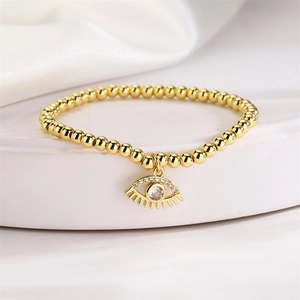Detailed macro view of 4mm gold beaded stretch bracelet with a zircon evil eye charm