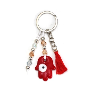 Close-up of red Hamsa hand keychain with evil eye, beads, and vibrant silk tassels