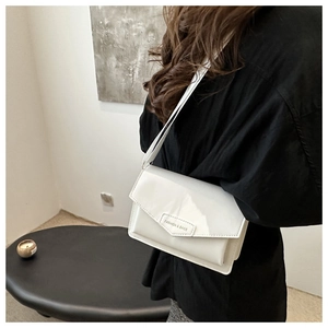 Detail of white patent leather flap bag with decorative triangular clasp buckle