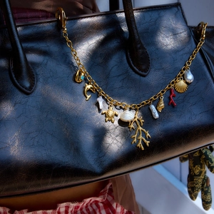 Detail of gold-plated ocean charms with dolphin, turtle, shell and pearl on a bag