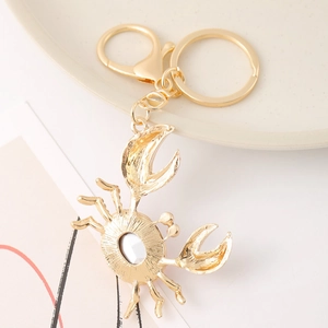 Golden crab keychain with sparkling crystal rhinestones and lobster clasp on a beige plate