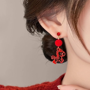 Elegant red pony drop earrings with velvet ball and gold-tone studs worn by a female model