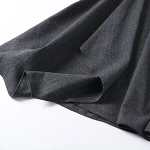 Gros plan du tissu épais en mélange de laine gris foncé et du drapé de la jupe évasée