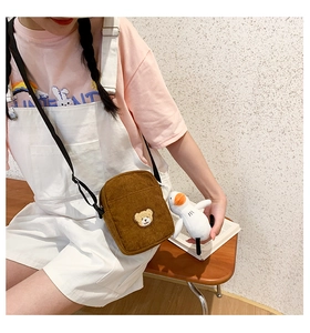 Detail of corduroy crossbody bag with bear embroidery and a plush duck charm