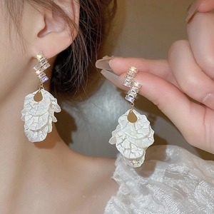 Close-up of gold shell flower fringe earring with rectangular zircon on woman's ear