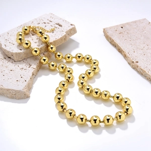 Minimalist 18K gold beaded necklace with polished spheres on travertine stones