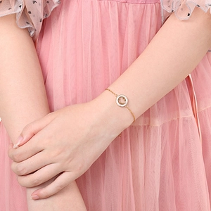 Elegantes goldenes Titanstahl-Armband mit Diamant-Smile-Anhänger am Handgelenk mit rosa Kleid