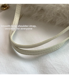 Detail of white faux fur bag showing adjustable leather strap with neat stitching