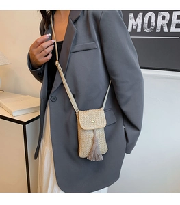 Detailed shot of beige straw crossbody phone bag with fringe tassel and magnetic closure