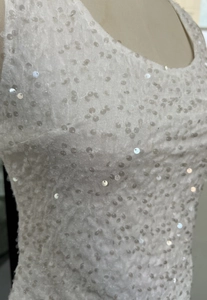 Close-up of white sequin fabric detail on elegant sleeveless top with shimmering finish