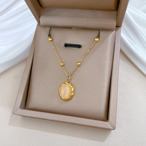 Macro detail of gold-plated titanium necklace with oval cat eye stone in jewelry box