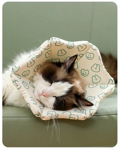Close-up of soft padded cat recovery collar with green smiley and rabbit patterns