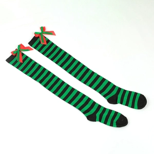 Detailed close-up of green and black striped over-knee socks with festive red satin bows