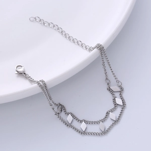 Minimalist silver double-layered chain anklet with polished rhombus charms on white ceramic