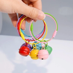 Hand holding colorful lacquered metal bell keychains with coated steel wire loops