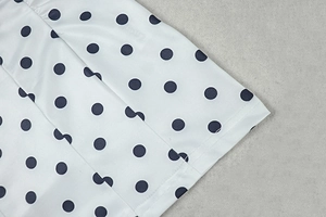 Macro shot of polka dot pattern and neat hem stitching on a white sleeveless dress